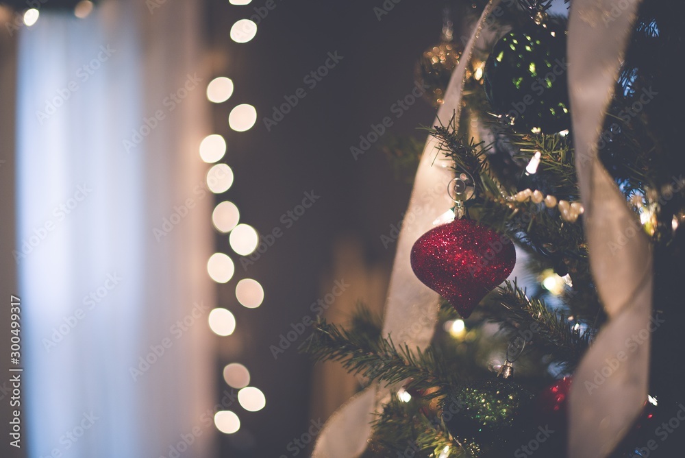 Closeup of a red ornament on the Christmas tree with bokeh lights - obrazy, fototapety, plakaty 
