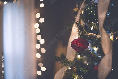 Closeup of a red ornament on the Christmas tree with bokeh lights