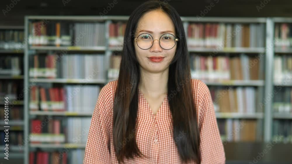 Woman reading a book in library. Portrait of college girl reading book in library. A young Asian female student searches for a book for her research project. Woman reading a book in library. Portrait of college girl reading book in library. A young Asian female student searches for a book for her research project.