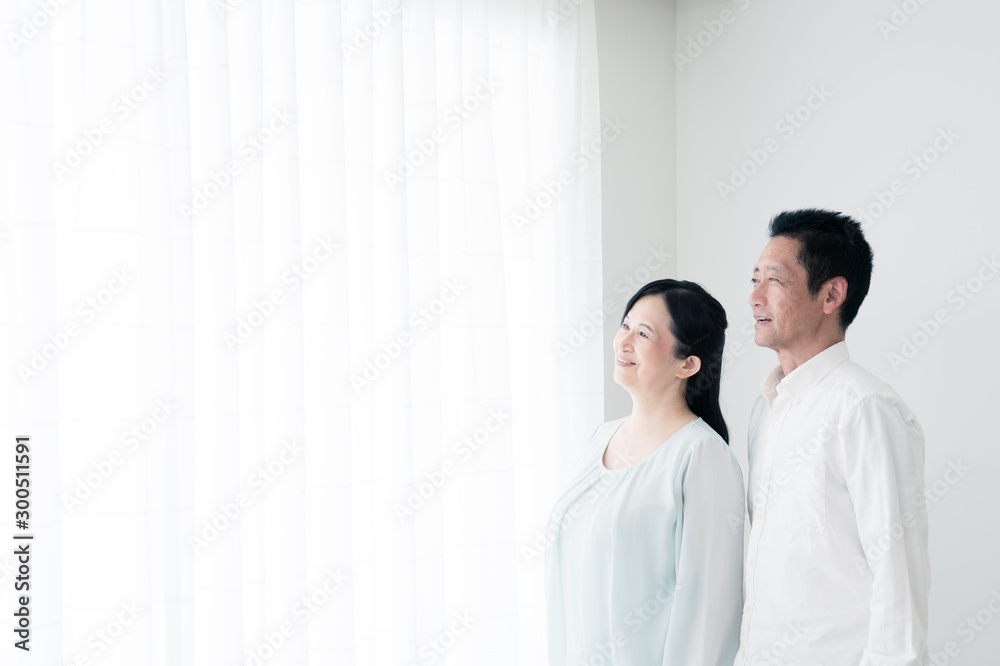 窓際に立つシニア夫婦 窓際に立つシニア夫婦