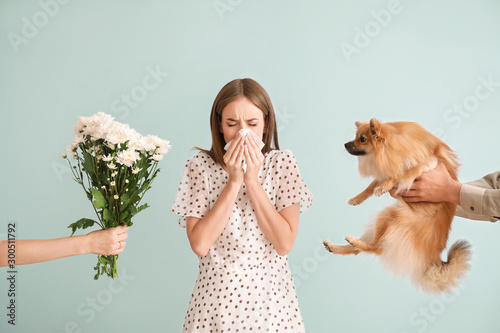 People giving flowers and dog to young woman suffering from allergy on light background © Pixel-Shot
