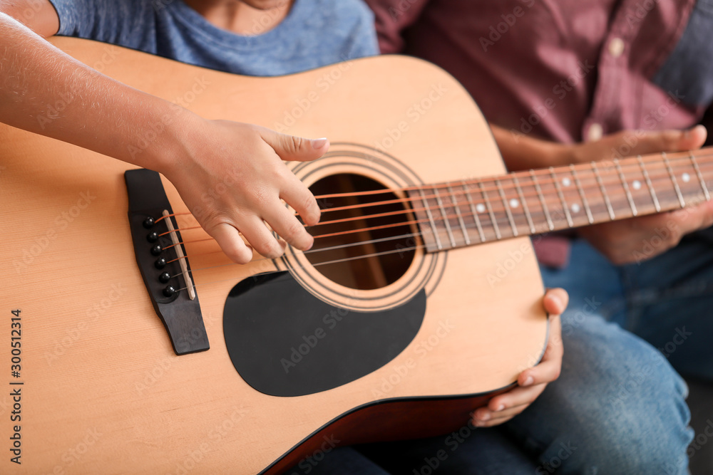 Fototapeta premium Little boy playing guitar at home, closeup