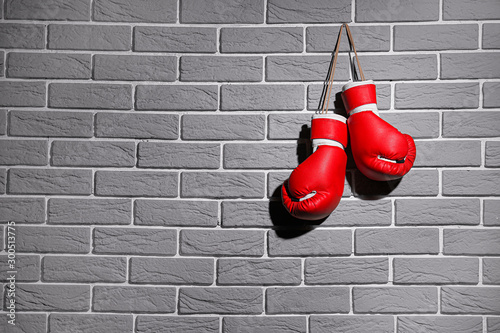 Pair of boxing gloves hanging on brick wall © Pixel-Shot