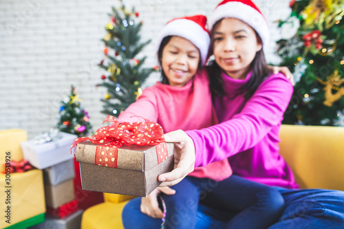 Cute asian child girl with her mother holding beautiful gift box and giving in Christmas celebration