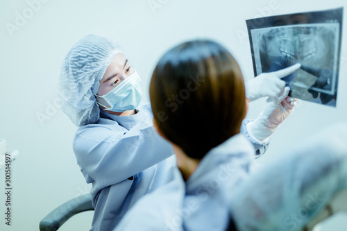 Принти на полотні Female dentist shows the x-ray of the patient's teeth in the dental clinic