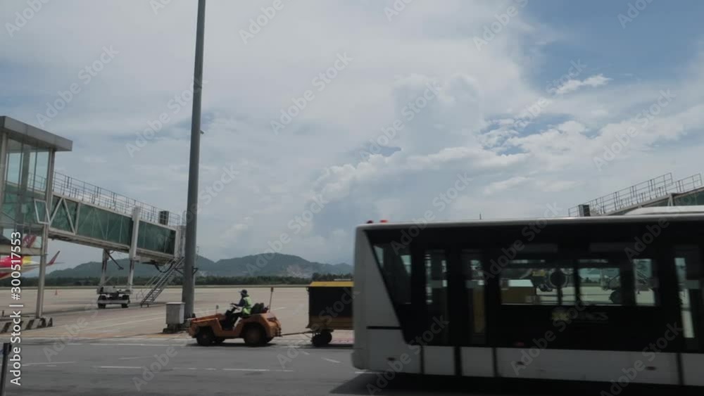 Dà Nang, Hai Chau District / Vietnam - 30.05.2019 Various airport service equipment passes by camera with a view of the runway, airplanes, flight bridge, mountains and clouds.