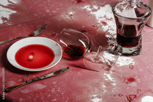 Broken goblets and broken glass on a table filled with red wine.