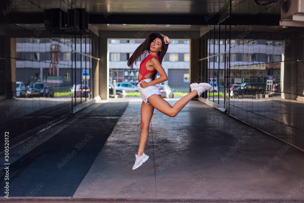Young brunette woman jumping in arch of building. Young brunette woman jumping in arch of building.