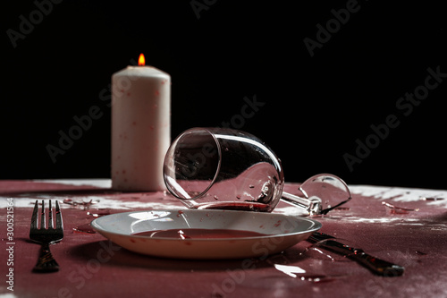 Broken goblets and broken glass on a table filled with red wine.