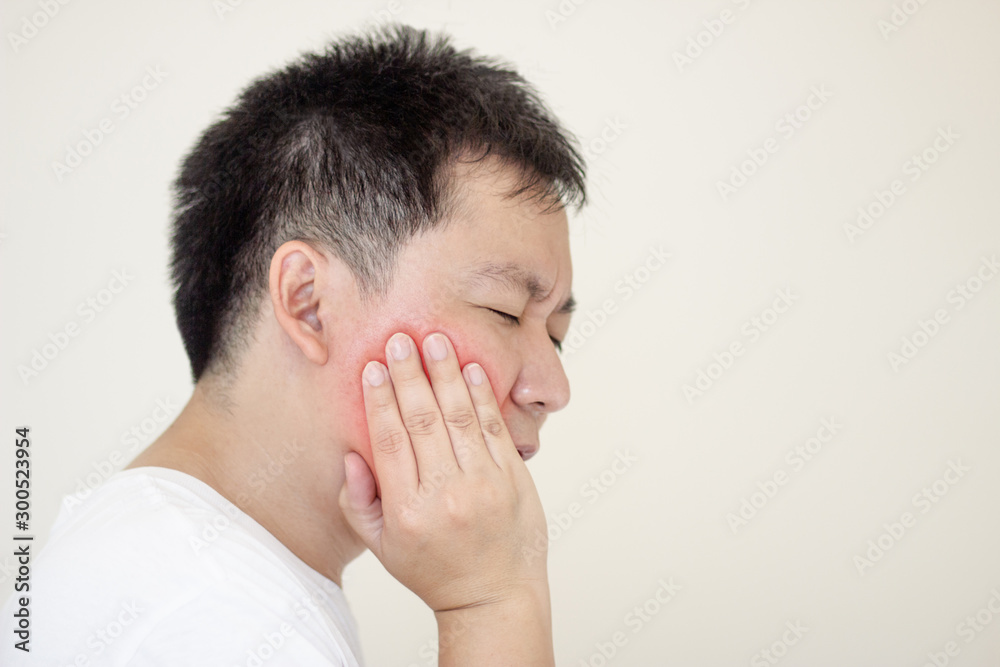 Indoor shot of young male feeling pain, holding his cheek with hand, suffering from bad toothache.Concept healthcare and medical. Indoor shot of young male feeling pain, holding his cheek with hand, suffering from bad toothache.Concept healthcare and medical.
