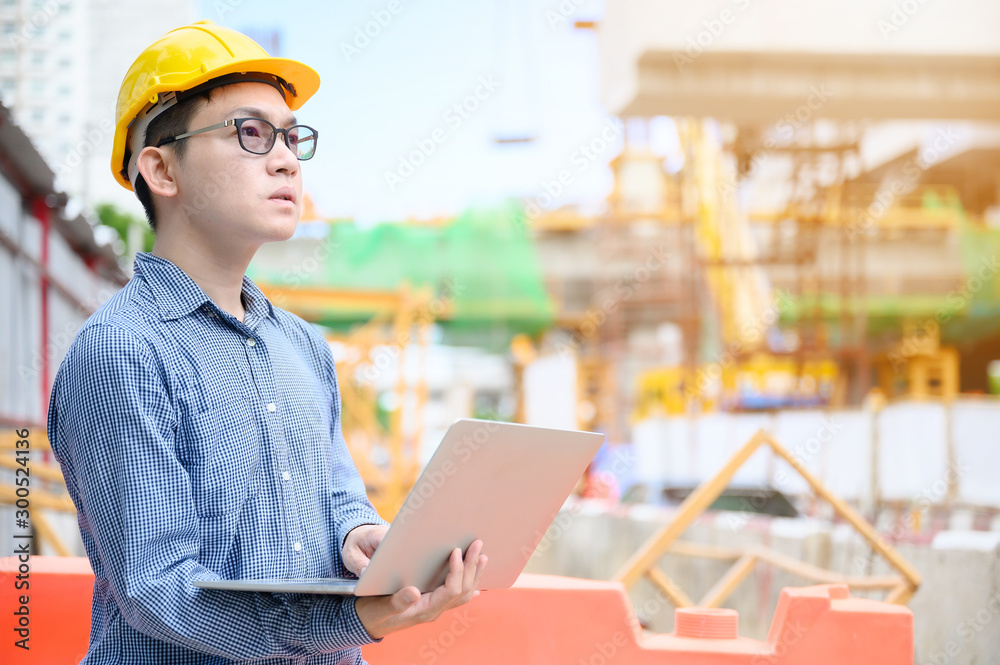 Young asian engineers are working on the construction site. Wear a yellow helmet safety. Hand holding computer laptop Young asian engineers are working on the construction site. Wear a yellow helmet safety. Hand holding computer laptop