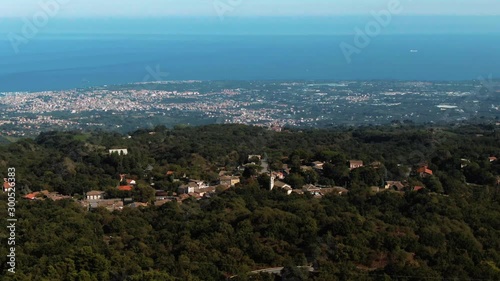 Aerial tilt up view of the small town of Fornazzo on mount Etna and the East coast of Sicily photo