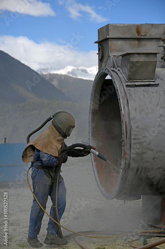Foto engineer sandblasting a steel casing