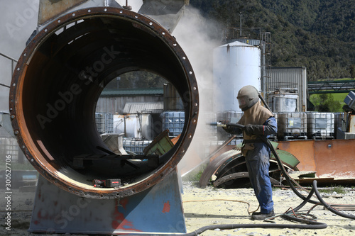 engineer sandblasting a steel casing