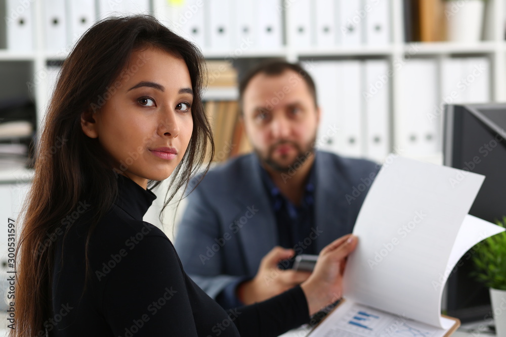 young beautiful woman sit on chair at table in office in cabinet of her boss hold binder in arms young beautiful woman sit on chair at table in office in cabinet of her boss hold binder in arms