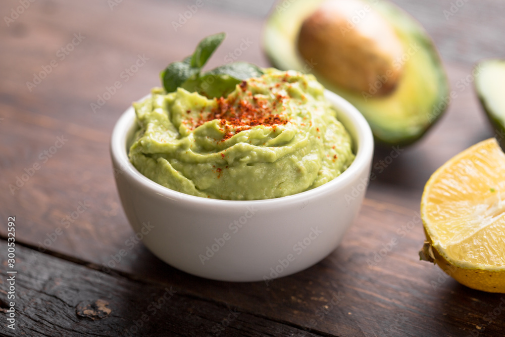 Bowl of green hummus, delicious cream of chickpeas and avocado on a wood background. Bowl of green hummus, delicious cream of chickpeas and avocado on a wood background.