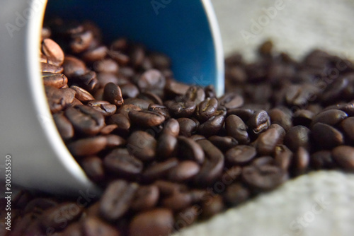 coffee beans in the white cup on the beige background close-up