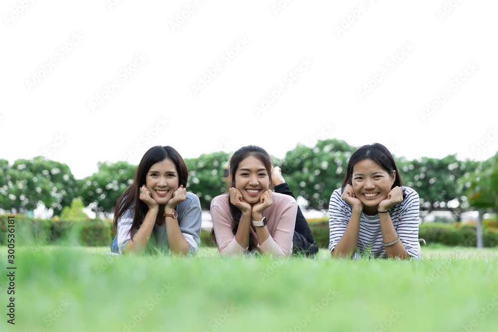 Group Cheerful young Asian woman in casual clothes three people laying down on grass together in the park. Look at the camera. Happy vacations. with Copy space Group Cheerful young Asian woman in casual clothes three people laying down on grass together in the park. Look at the camera. Happy vacations. with Copy space