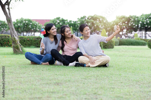 Group Cheerful young Asian woman in casual clothes three people selfie with smartphone together in the park. Happy vacations