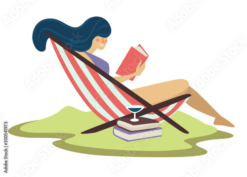 Woman on beach lounger and reading book with martini cocktail