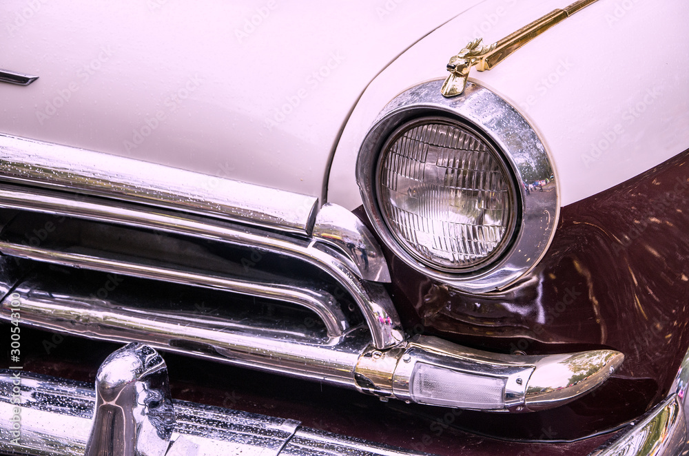 The front part of the retro car, a fragment of the brilliant design of the old means of transport, close-up, copy space, toned.