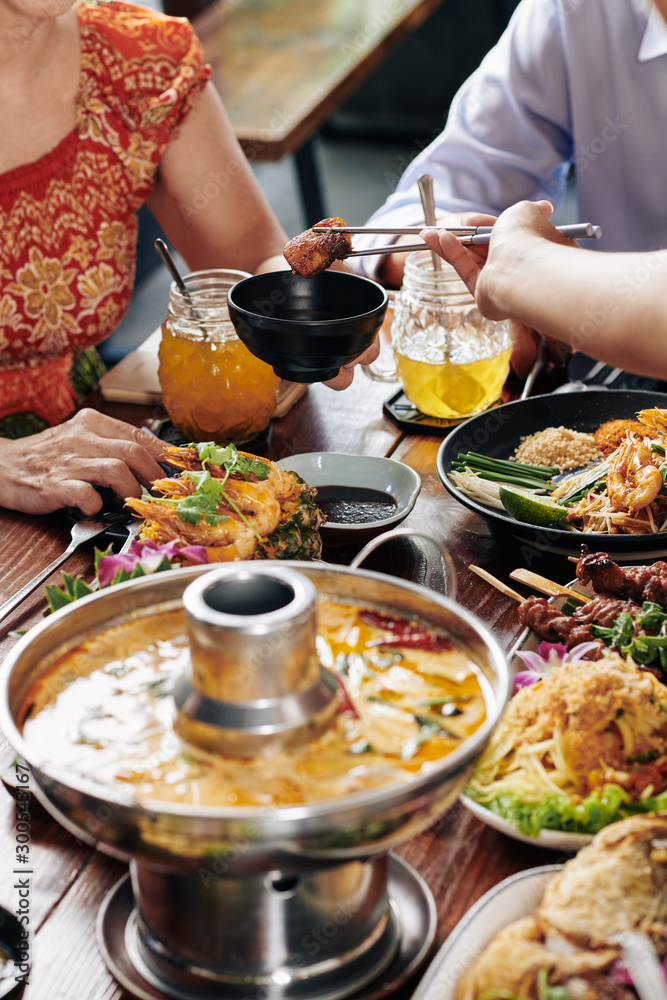 Group of people enjoying tasty dishes of Vietnamese cuisine during family dinner in restaurant Group of people enjoying tasty dishes of Vietnamese cuisine during family dinner in restaurant