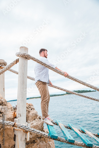 man walking by tourist suspension bridge crossing sea bay © phpetrunina14
