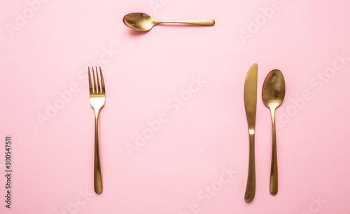 Panel kuchenny z motywem Gold cutlery set against pink background, formal place setting