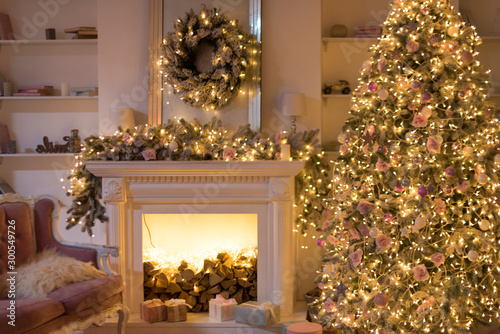 Warm cozy evening, Christmas eve, Christmas room with fireplace interior design, Xmas tree decorated by lights, gifts toys, garland lighting fireplace. Happy Winter Holidays, holiday living room. © Magryt