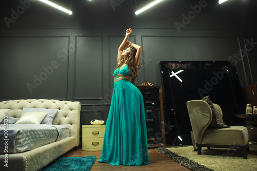 Vogue fashion style portrait of young beautiful pretty elegant rich woman wearing evening dress in luxury apartments