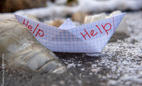 The paper boat marked help was stuck among the plastic bottles frozen in the water.