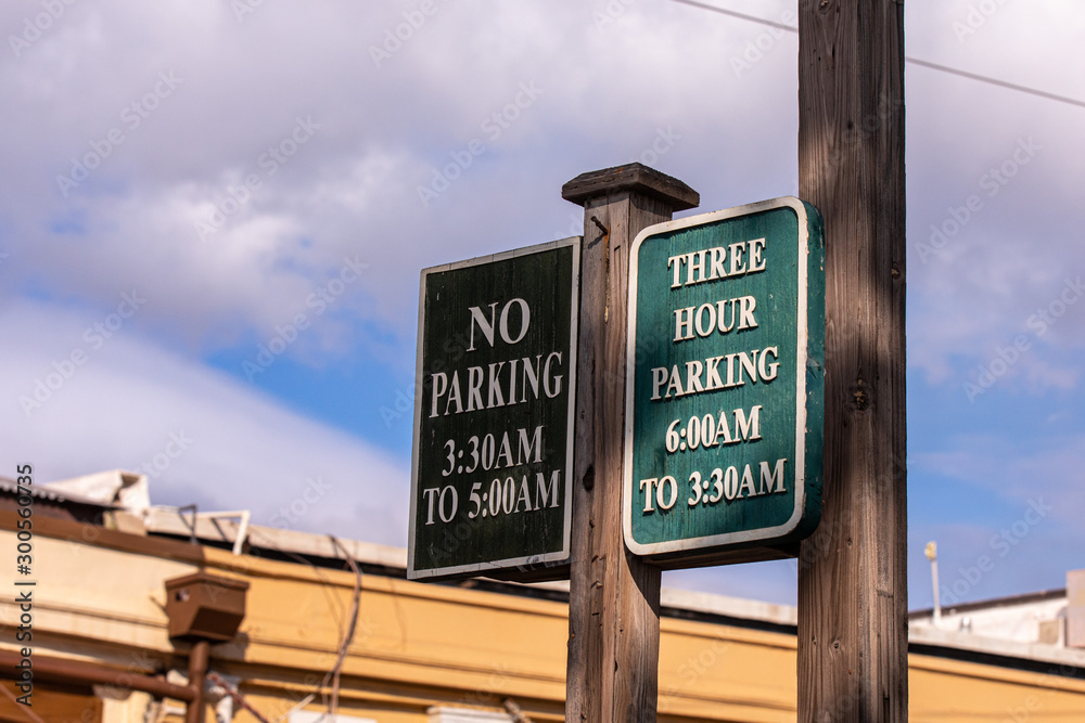 Fototapeta premium Posted parking sign on a street of Lahaina, Maui. A two side wooden sign read 