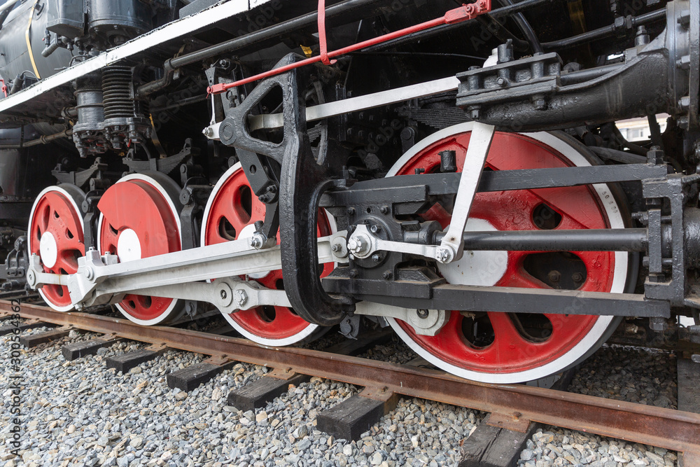 Close-up of a driving wheel of an old-fashioned steamed red-black painted vintage steam train