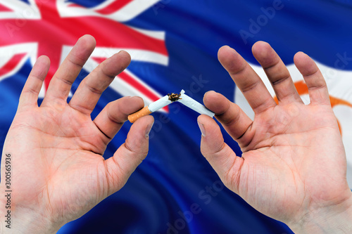 Anguilla quit smoking cigarettes concept. Adult man hands breaking cigarette. National health theme and country flag background.