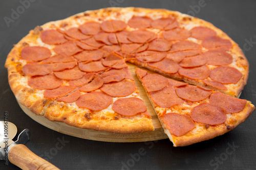 Tasty Pepperoni pizza over black background, side view. Close-up.