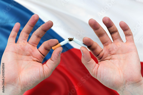 Czech Republic quit smoking cigarettes concept. Adult man hands breaking cigarette. National health theme and country flag background.