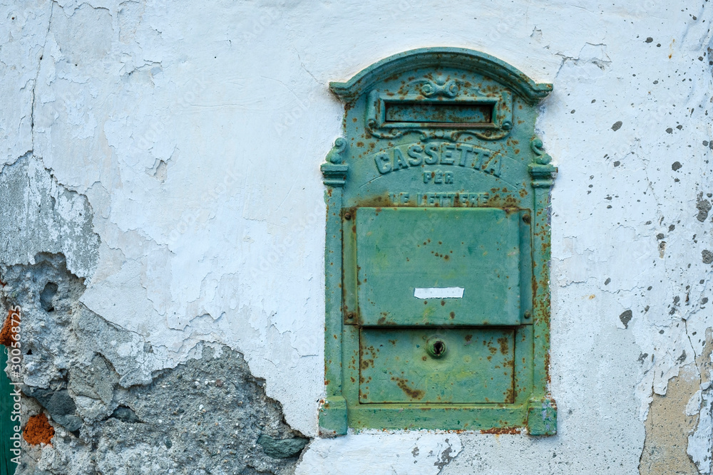 Old metal post box in a white weathered house wall in Piedmont, Italy