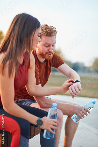 Modern couple making pause in an urban park during jogging / exercise. © astrosystem