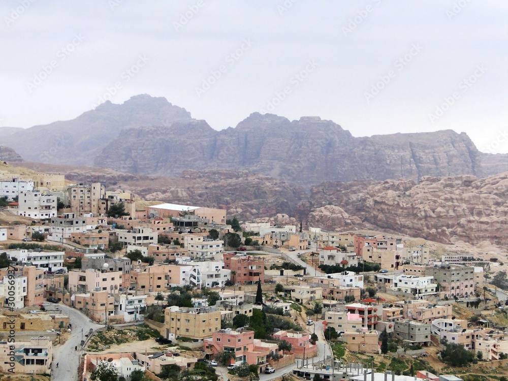 Panoramic view of cityscape in Petra in Jordan, misty mountains and houses in the morning. Petra has an UNESCO World Heritage Site with a historical archaeological park.