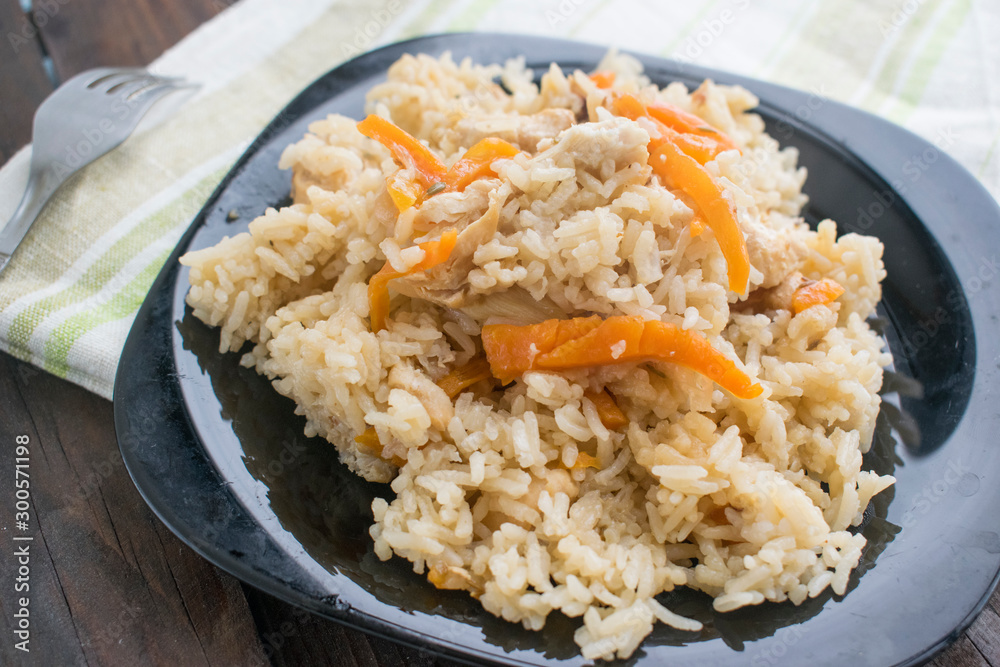 rice with meat and vegetables in a black plate on a wooden background rice with meat and vegetables in a black plate on a wooden background