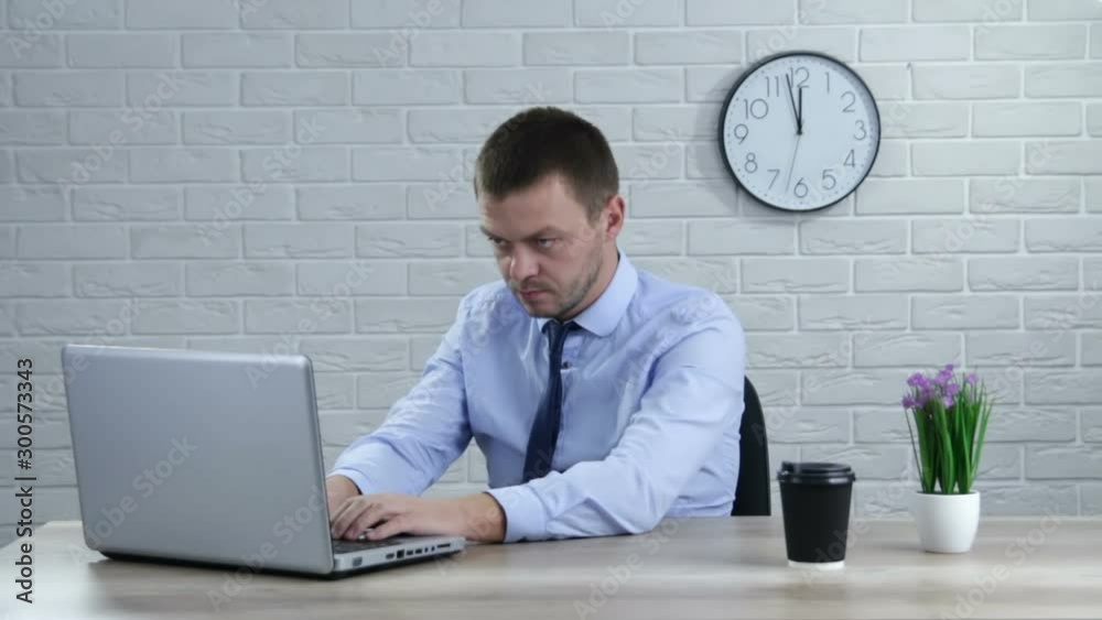 Businessman sitting at office desk working on laptop computer