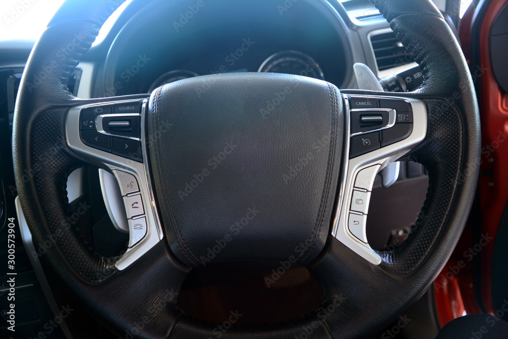 the black leather at middle of the steering wheel with cruise control and multi media controler button inside of new car passenger room