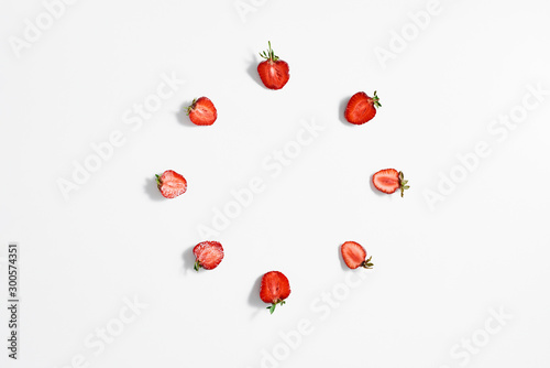 A circle of slices of fresh ripe strawberries on a white surface. Top view.