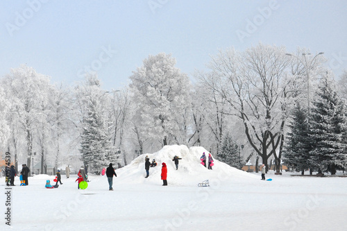 Children ride with their parents on a snow slide in the city square