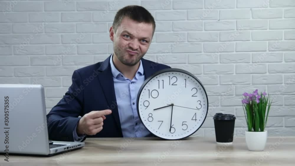 Business, people, time management and office concept - Businessman in suit holding clock showing a time Business, people, time management and office concept - Businessman in suit holding clock showing a time