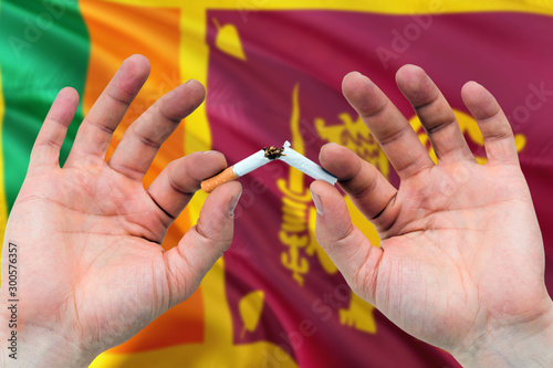 Sri Lanka quit smoking cigarettes concept. Adult man hands breaking cigarette. National health theme and country flag background.