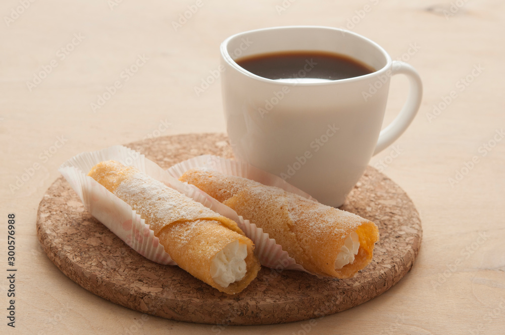 Sweet snack with coffee and waffle tubes on wood background Sweet snack with coffee and waffle tubes on wood background