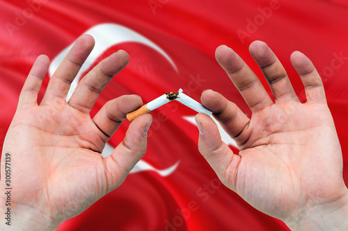 Turkey quit smoking cigarettes concept. Adult man hands breaking cigarette. National health theme and country flag background.
