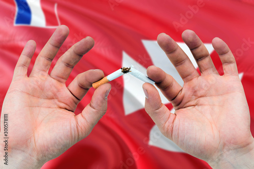 Wallis And Futuna quit smoking cigarettes concept. Adult man hands breaking cigarette. National health theme and country flag background.