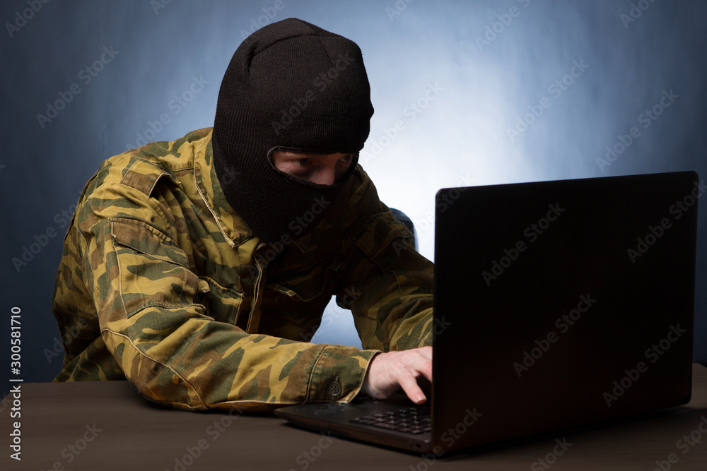 Masked cyber terrorist in military uniform hacking army intelligence Masked cyber terrorist in military uniform hacking army intelligence